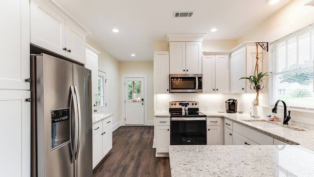 A modern kitchen with white cabinets, stainless steel appliances, and a granite countertop. - Our Nest at Spiller l Adorable Home near UA (Tuscaloosa)