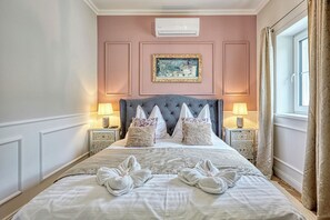A hotel room with a large bed, two bedside lamps, a picture on the wall, and a window with curtains. - Riverside boutique apartments next to the thermal bath (Mosonmagyaróvár)