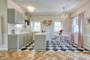 A modern kitchen with a central island, clear chairs, and a chandelier. - Riverside boutique apartments next to the thermal bath (Mosonmagyaróvár)