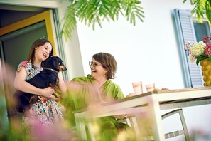 Una persona sosteniendo un perro, una mesa con objetos encima y una ventana con persianas.