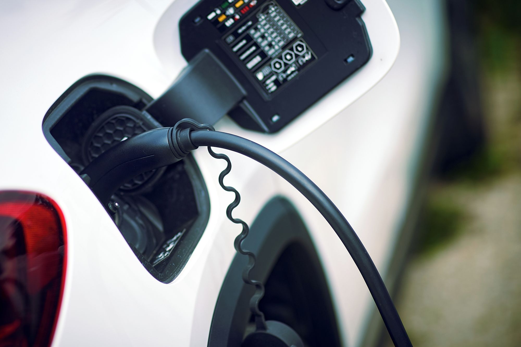 Primer pla d'un cable de càrrega per vehicle elèctric connectat a una estació de càrrega.