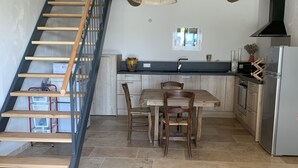 A kitchen with a wooden staircase, a dining table with chairs, and a hanging light fixture. - Bed and breakfast / gîte with SPA (Massages on reservation) (Domessargues)