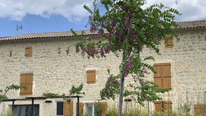 A stone building with a garden, outdoor seating, and a pergola. - Bed and breakfast / gîte with SPA (Massages on reservation) (Domessargues)