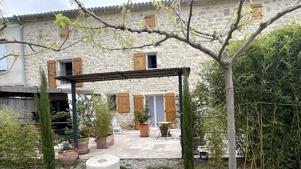A stone building with a covered patio area, potted plants, and outdoor furniture. - Bed and breakfast / gîte with SPA (Massages on reservation) (Domessargues)