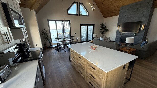 Een ruime keuken met een groot eiland, houten kastjes en een stenen openhaard.