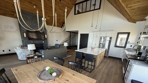 Een ruime keuken met een centraal eiland, een eetgedeelte met een houten tafel, en een moderne kroonluchter.