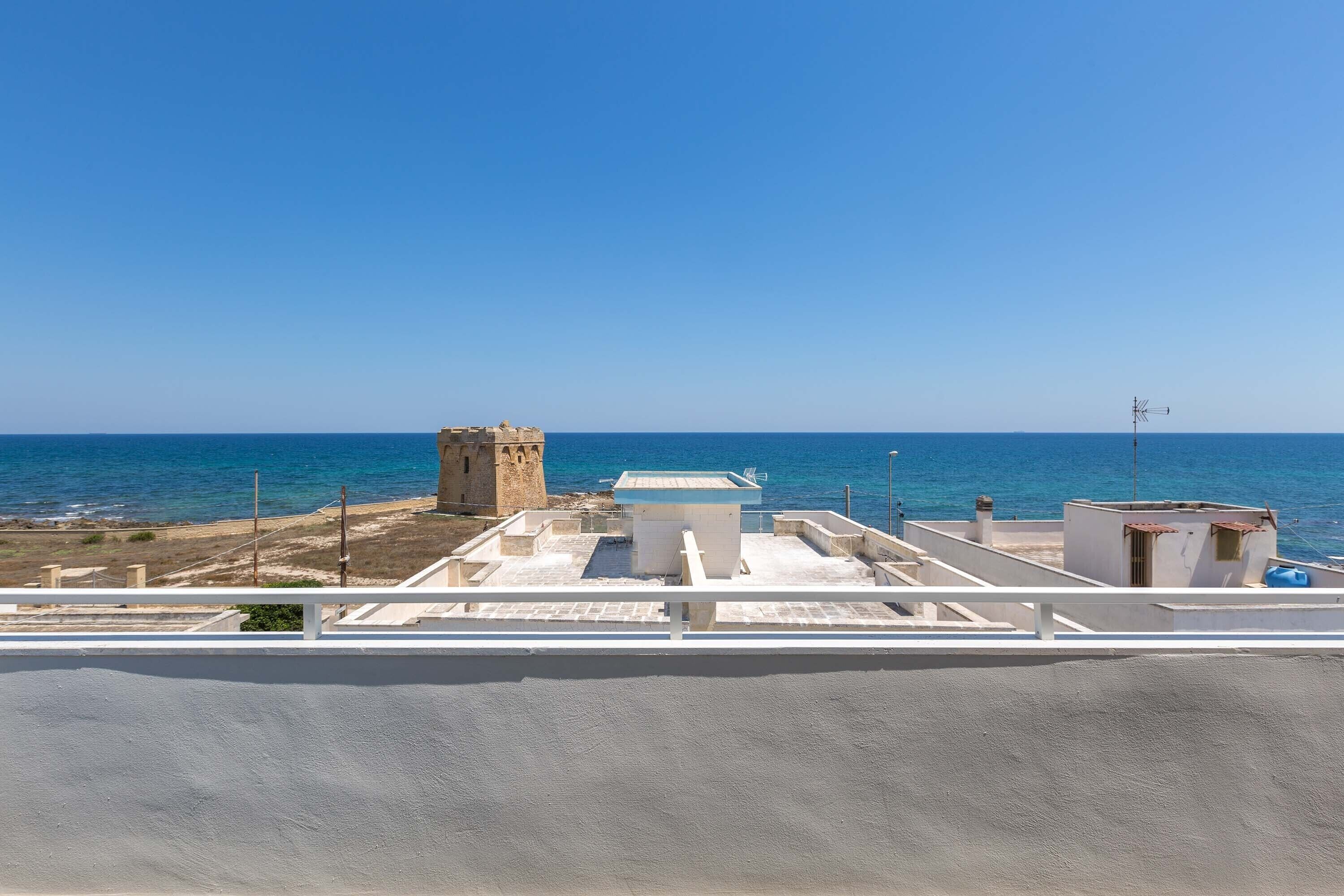 Vista costera con cielo despejado, una torre y un edificio de techo plano.