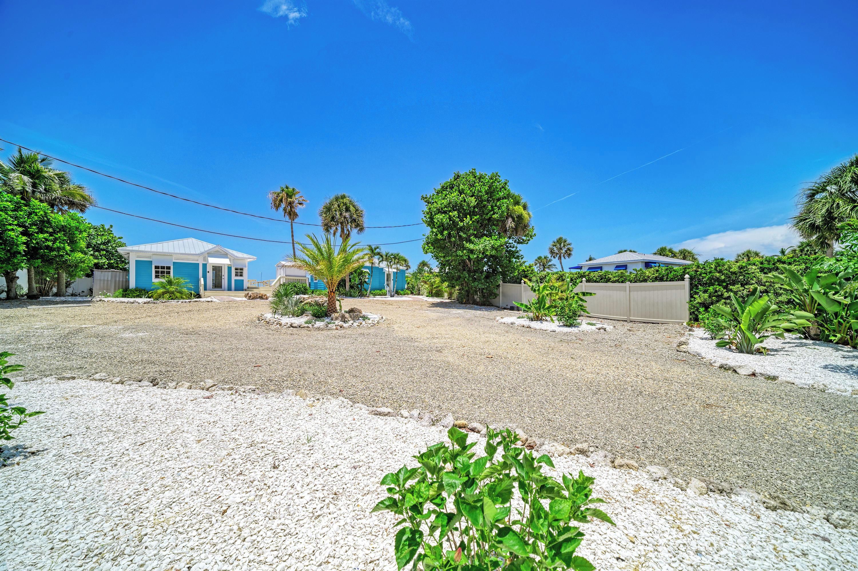 A residential area with houses, a gravel driveway, and palm trees.