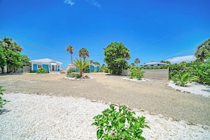 A residential area with houses, a gravel driveway, and palm trees.