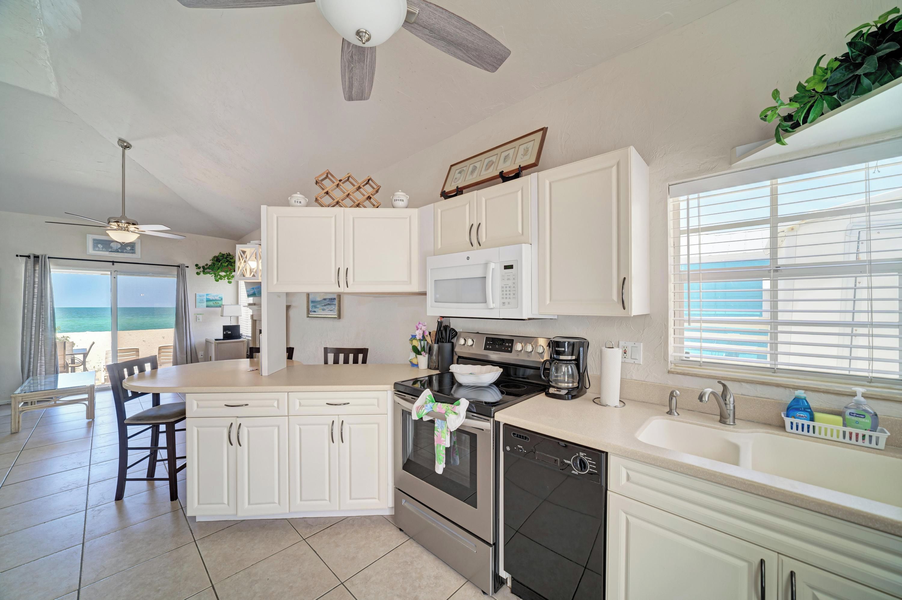 A kitchen with white cabinets, a microwave, a stove, and a coffee maker.