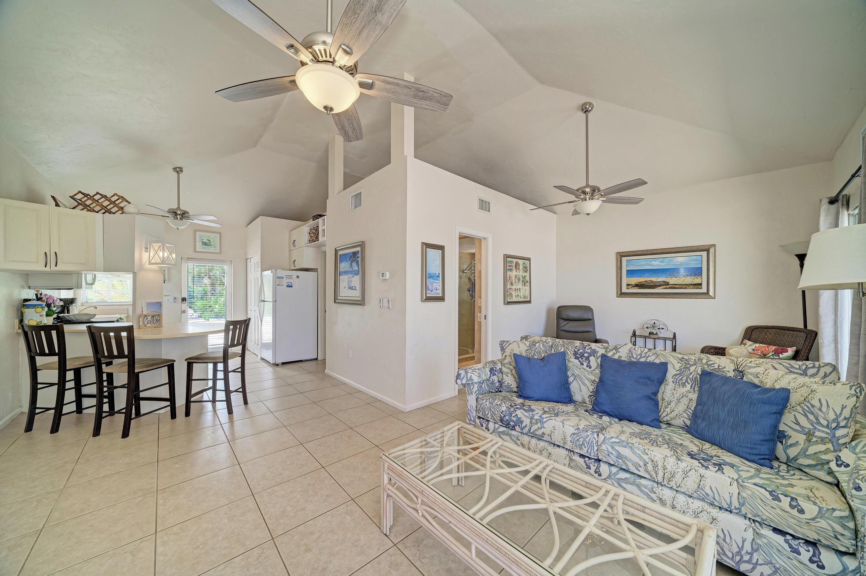 A spacious living area with a sofa, a glass coffee table, and a ceiling fan.