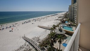 Un resort en la playa con zona de piscina, terraza de madera y vistas al océano.