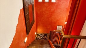 A staircase with a red wall, a patterned rug, and a wooden railing. - Loft Escape Artistic (Surprise)