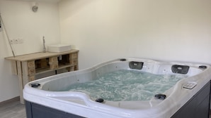 Uma banheira de hidromassagem em um quarto com teto inclinado, um armário de madeira e um claraboia.