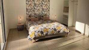 Quarto com cama, duas luminárias de cabeceira, guarda-roupa e uma janela grande.