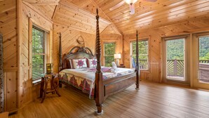 A spacious bedroom with a large bed, wooden ceiling, and multiple windows. - Private cabin with stunning views near Pigeon Forge (Sevierville)