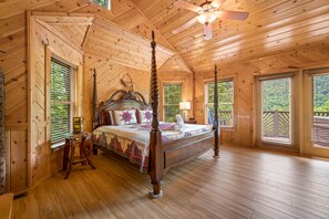 Ein geräumiges Schlafzimmer mit einem großen Bett, Holzbalkendecke und mehreren Fenstern.