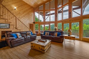 Un salon spacieux doté de parquets en bois, de grandes fenêtres et d’un escalier.