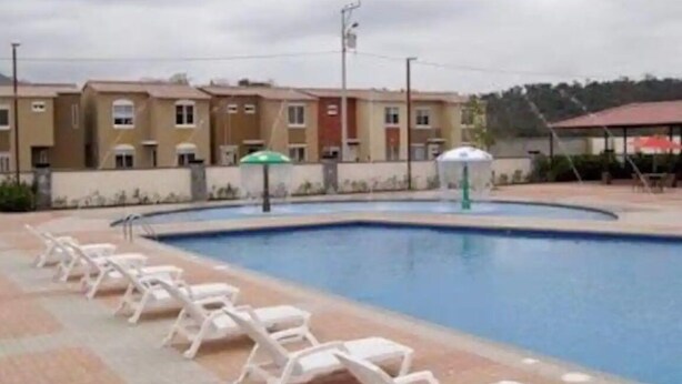 Una piscina con sillas de descanso y un edificio al fondo.
