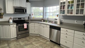 A kitchen with white cabinets, stainless steel appliances, and a window with a view of the outdoors. - 3/2 with Heated Pool - Tranquil Tropical Escape
(Sebastian)