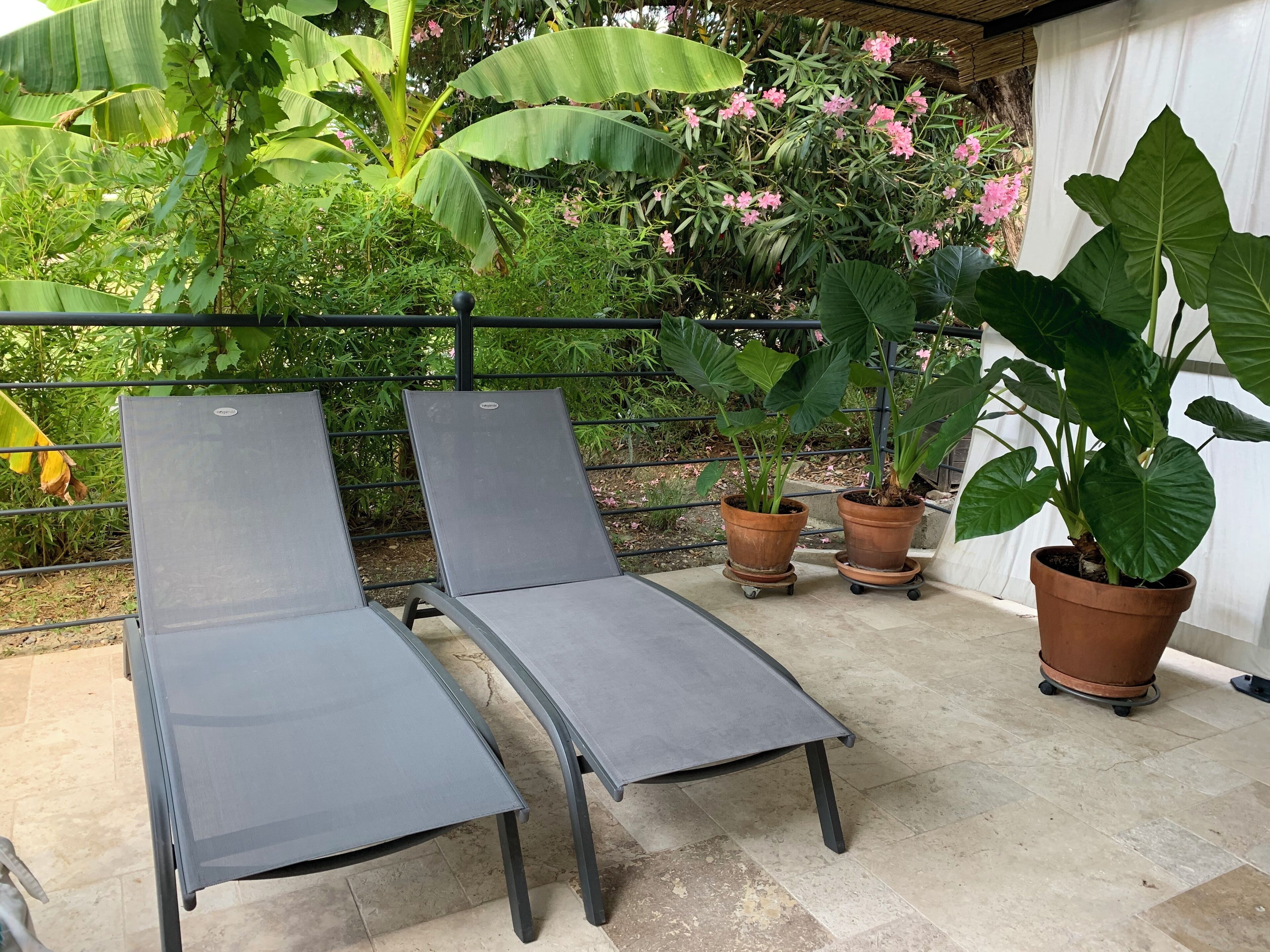 En terrasse med to liggestole og tre plantekasser.