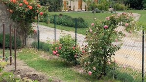 A stone building with a garden in front, featuring rose bushes and a fence. - Bed and breakfast / gîte with SPA (Massages on reservation) (Domessargues)