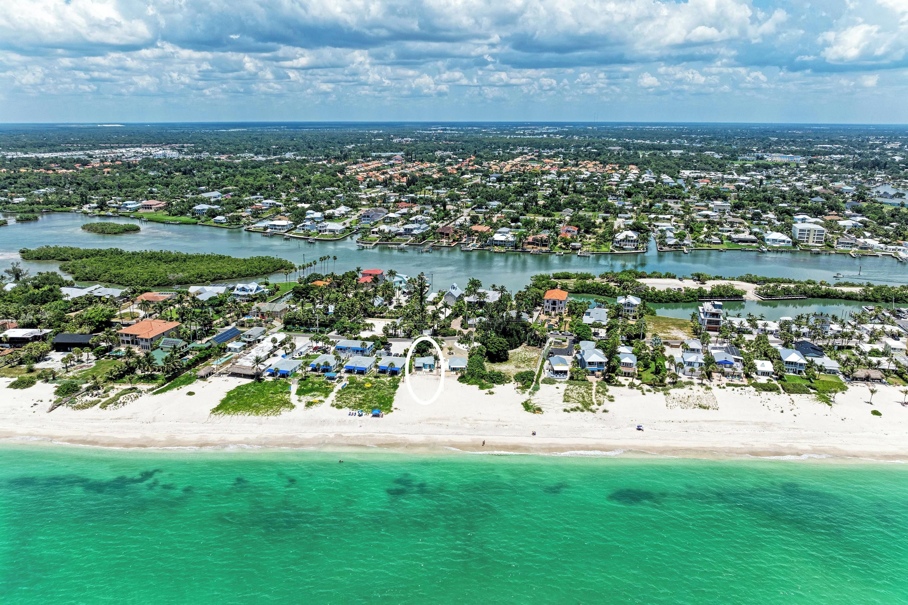 Luchtbeeld van een kustgebied met woonhuizen, een strand en een jachthaven.