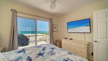 Quarto com vista para a praia, ventoinha no teto, televisão e cómoda.