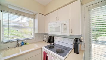 A compact kitchen with a microwave, stove, and coffee maker.