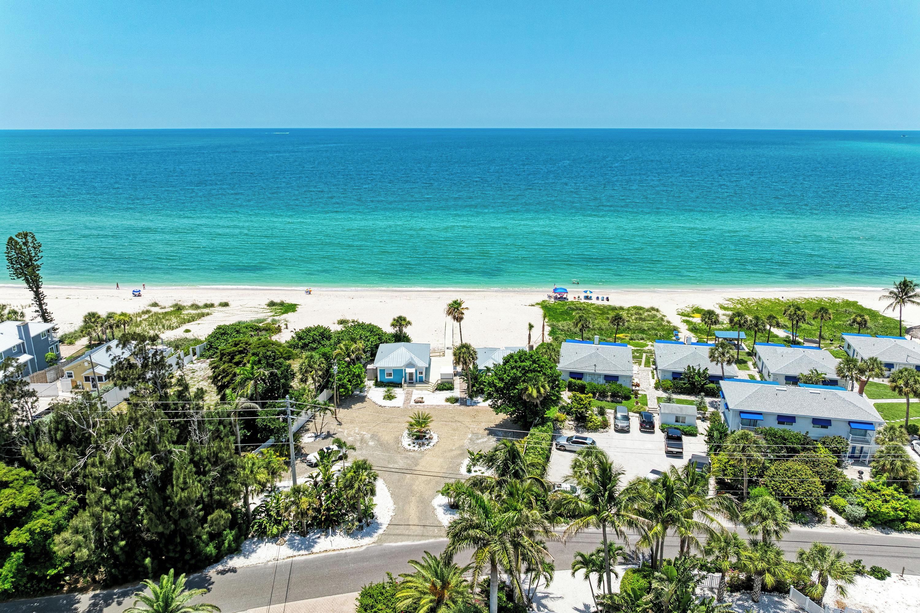 A coastal residential area with beachfront properties, a clear view of the ocean, and a road leading to the beach.