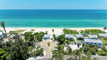 A coastal residential area with beachfront properties, a clear view of the ocean, and a road leading to the beach.
