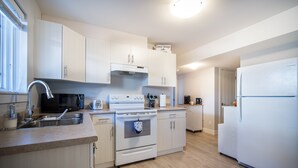 Una cocina moderna con armarios blancos, un lavamanos de acero inoxidable, un microondas, un horno y un refrigerador.