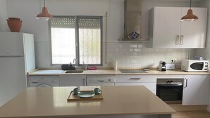 Une cuisine moderne avec des armoires blanches, un îlot central, un four à micro-ondes et un évier.