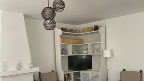 Un salon avec une cheminée, des canapés blancs, un téléviseur et une bibliothèque.