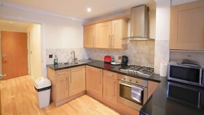 A modern kitchen with wooden cabinets, a stainless steel stove, and a microwave. - Lovely 2-bed Apartment in London (London)