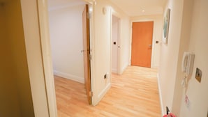 A hallway with wooden flooring, white walls, and doors leading to other rooms. - Lovely 2-bed Apartment in London (London)