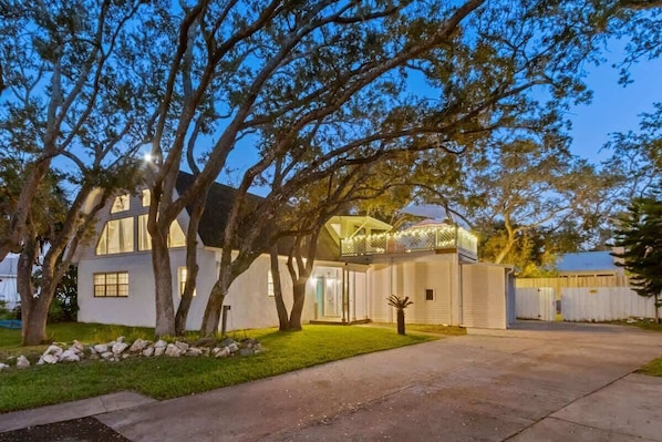 A modern two-story house with a covered patio, a well-maintained lawn, and a driveway leading to the entrance.