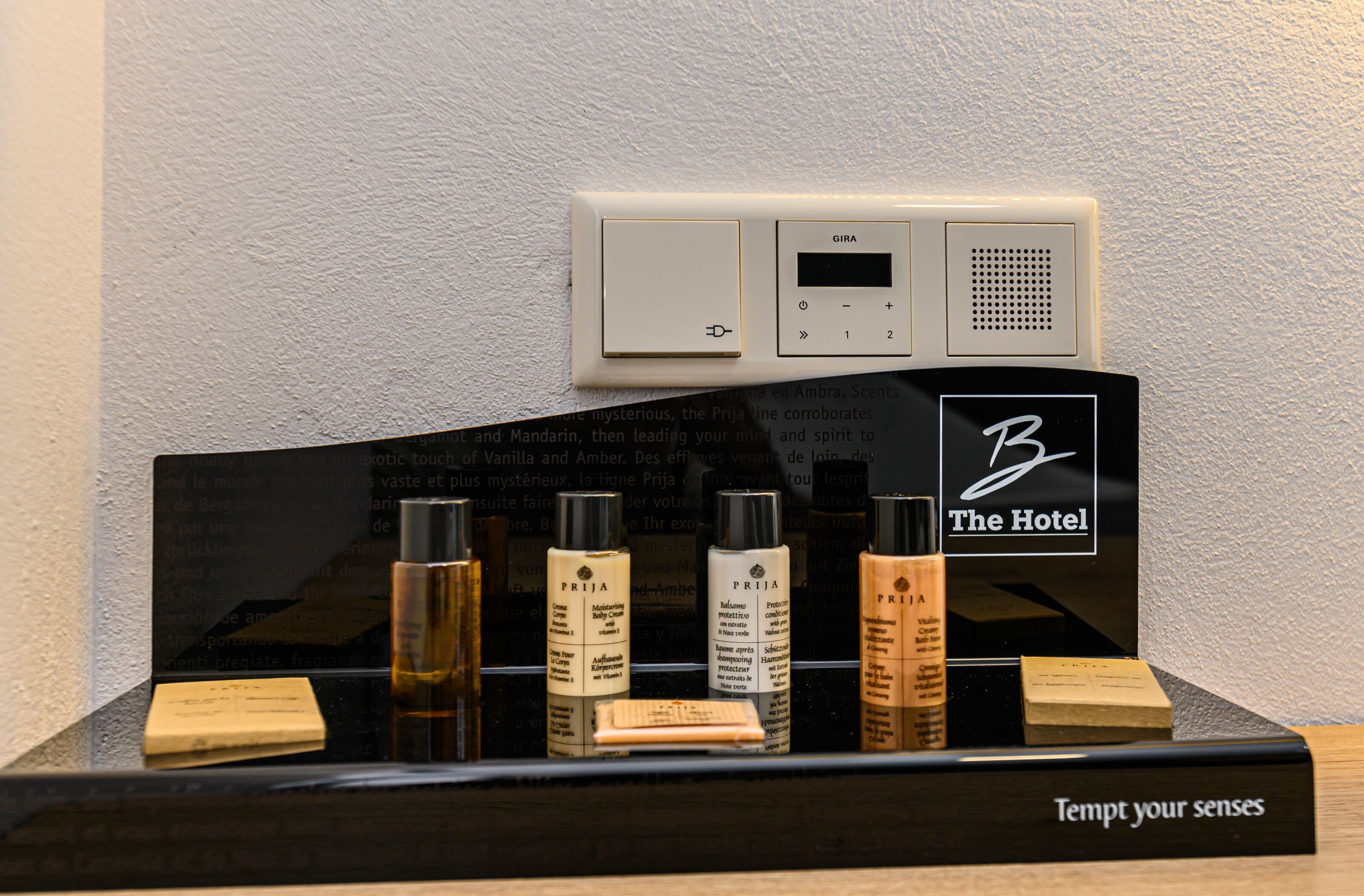 A display of hotel amenities including a thermostat, a digital clock, and various toiletries.
