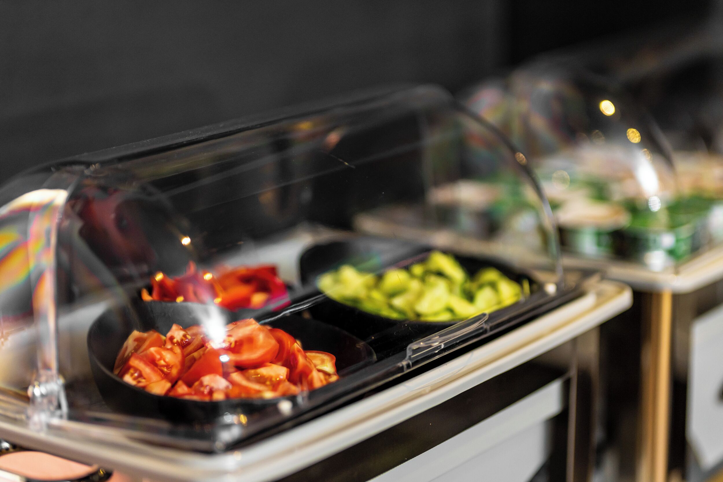 Un bufé con diversas opciones de comida cubiertas por plástico transparente.