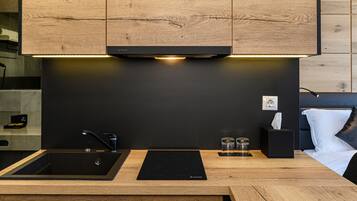 Una cocina moderna con armarios de madera, encimera negra, un lavabo y una placa de inducción integrada.