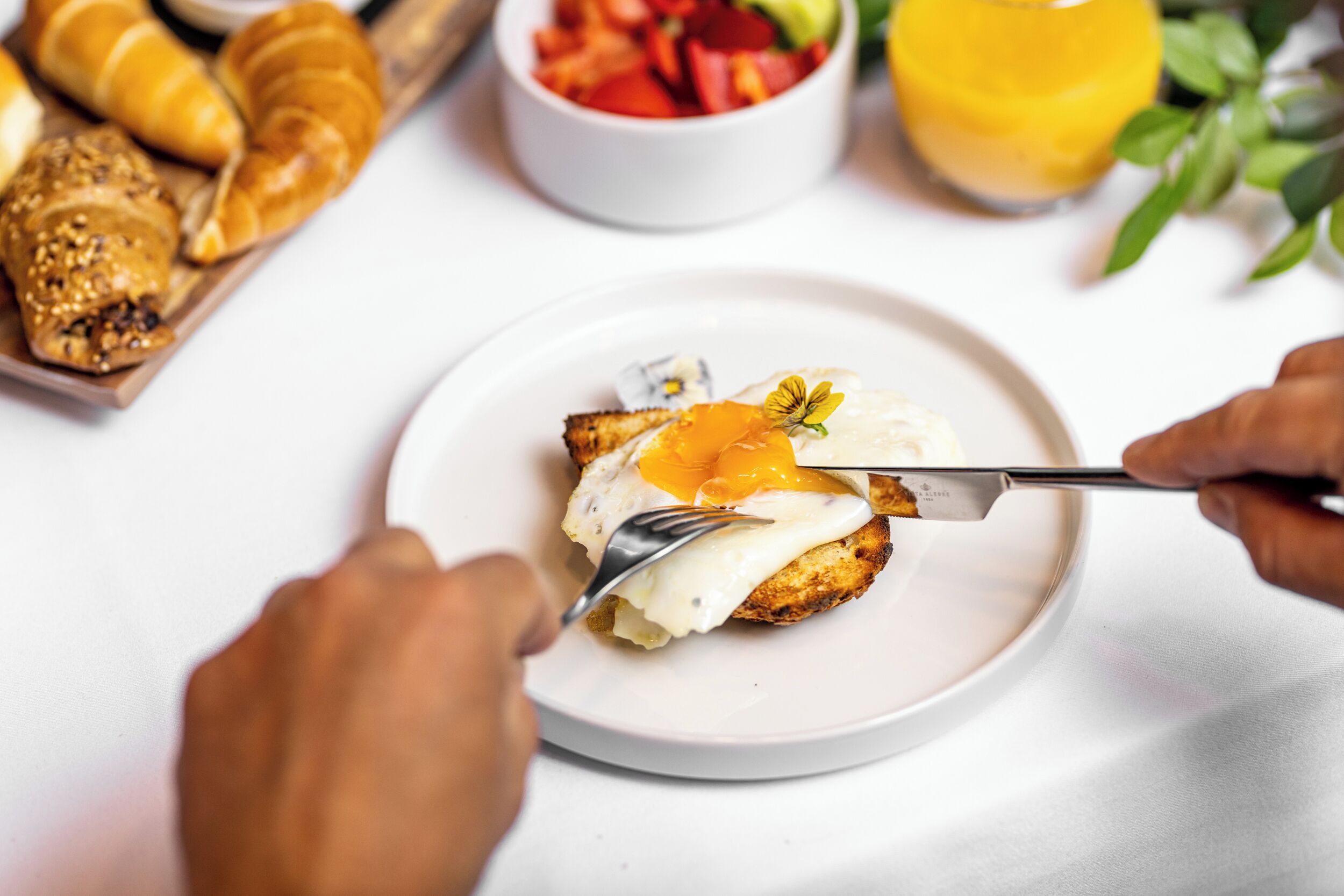A breakfast plate with a fried egg, toast, and a small bowl of fruit.