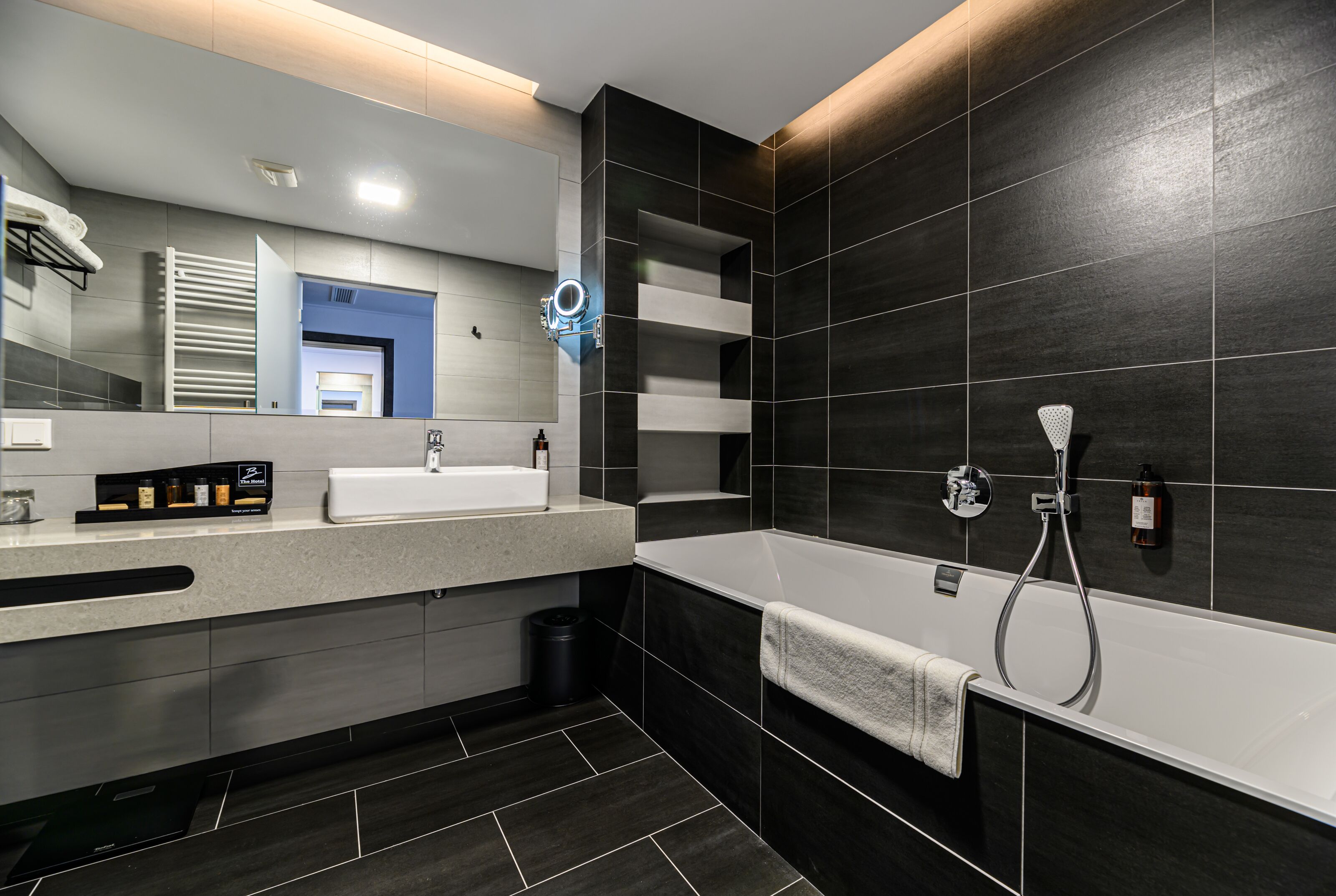 A modern bathroom with a large bathtub, a double sink vanity, and a mirror with a built-in light.