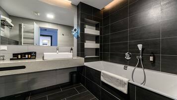 A modern bathroom with a large bathtub, a double sink vanity, and a mirror with a built-in light.
