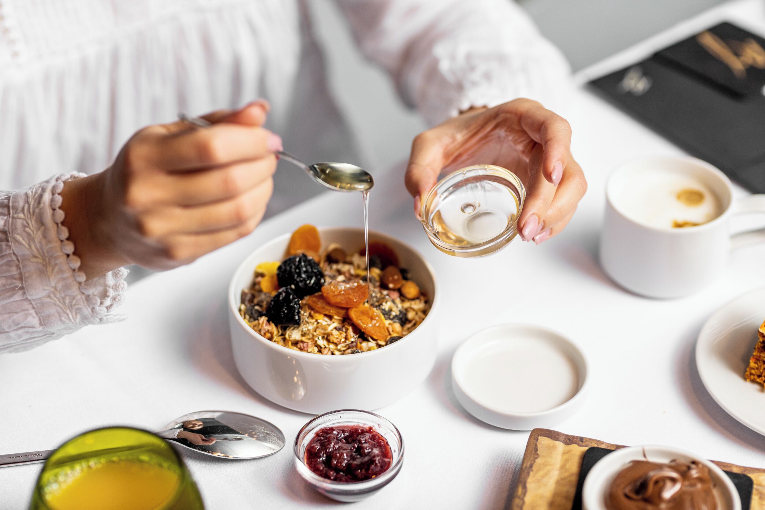 Ein Frühstückstisch mit einer Schüssel Müsli, einem Glas Saft und einer Kaffeetasse.