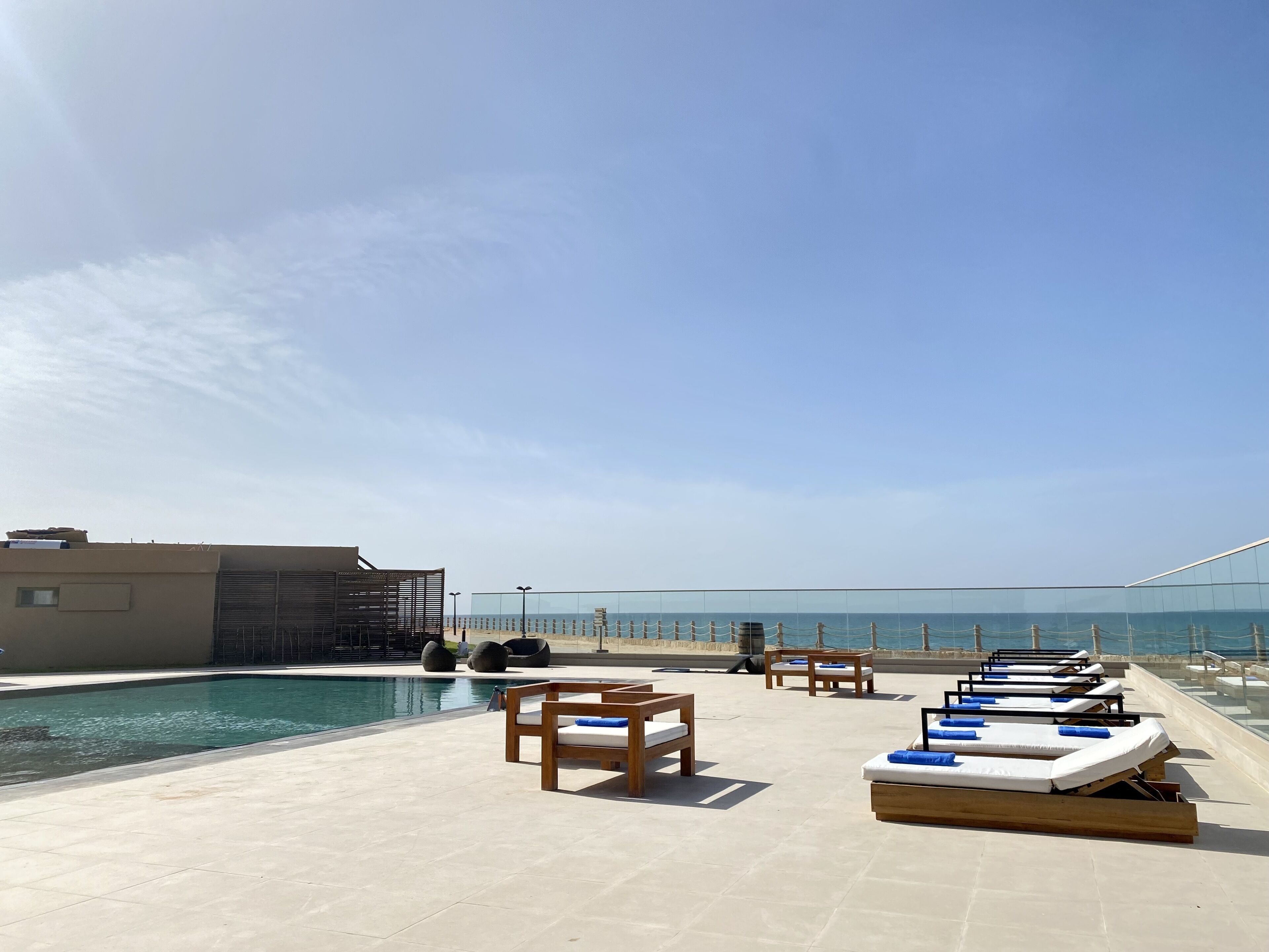 A rooftop pool area with lounge chairs and a view of the ocean.