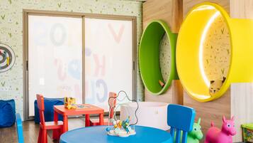 Ein Kinderzimmer mit einem runden Tisch, blauen Stühlen und bunten Spielsachen.