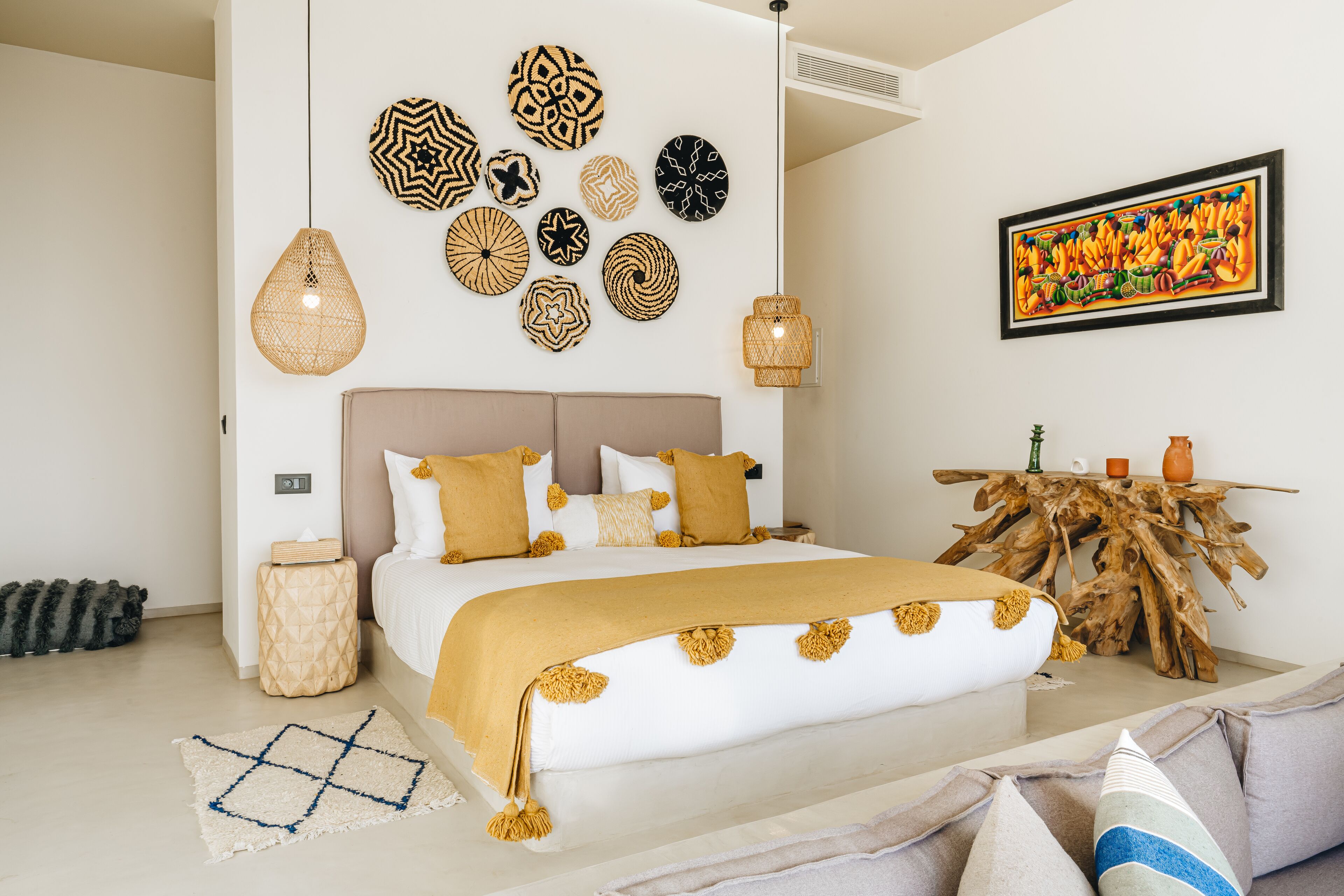 A bedroom with a bed, decorative wall art, a wooden table, and a unique wall-mounted light fixture.