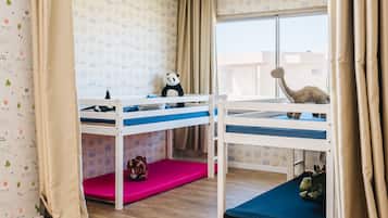 Cozy bedroom with a bunk bed setup, featuring two beds and a playful wallpaper pattern.
