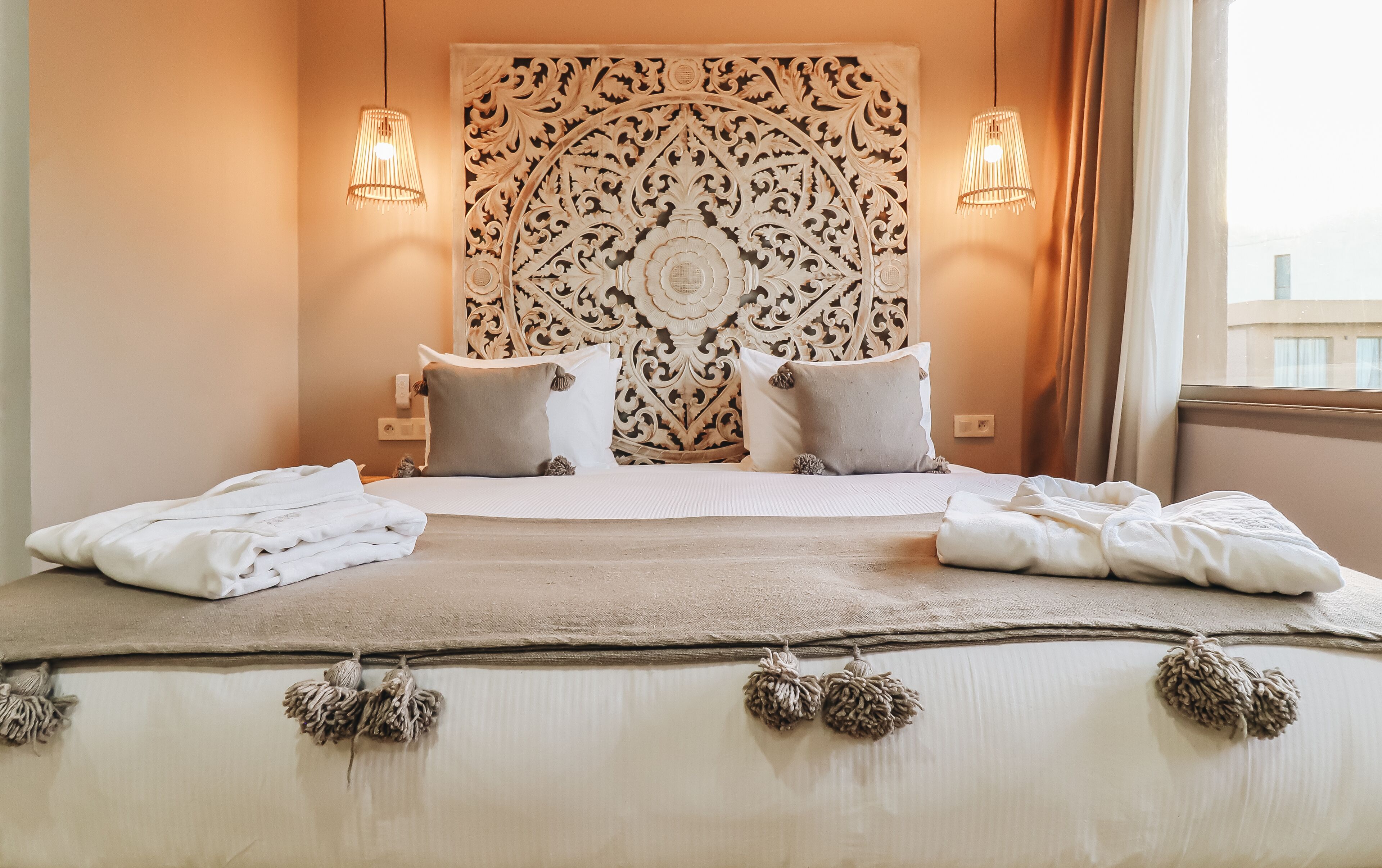A neatly made bed with white linens, two bedside lamps, and a decorative headboard.