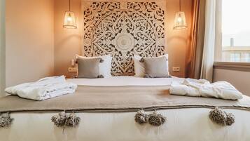 A neatly made bed with white linens, two bedside lamps, and a decorative headboard.